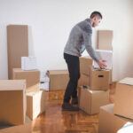 Handsome man spending his time unpacking boxes at the new apartment.